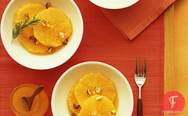 Laranjas fatiadas com xarope de laranja e avelãs cristalizadas