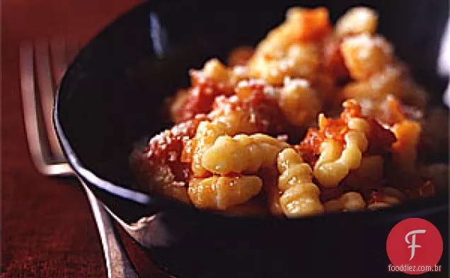 Bolinhos de batata minúsculos com tomate, cebola e molho Guanciale