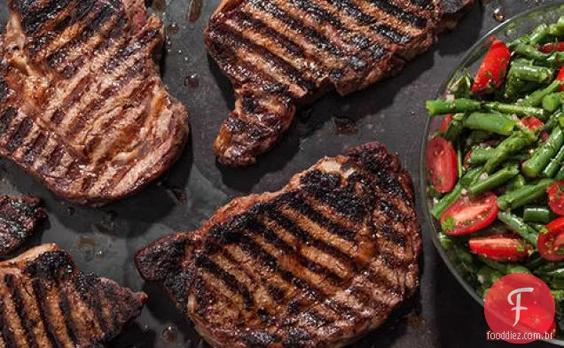 Bifes de costela grelhados esfregados com especiarias com salada de feijão verde e tomate cereja