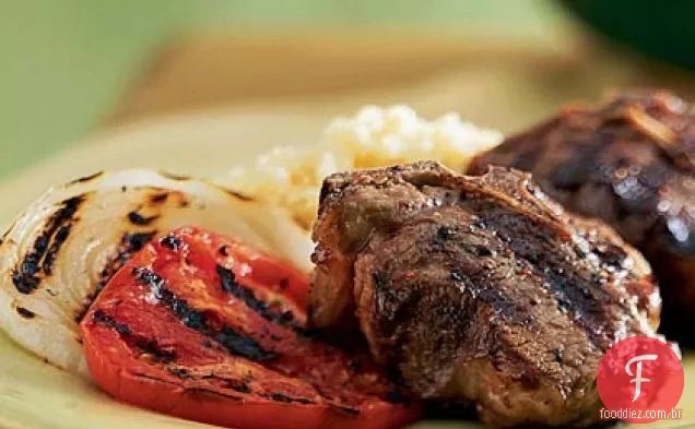 Costeletas de cordeiro grelhadas com tomate e cebola
