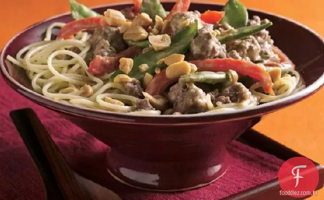 Carne de amendoim tailandesa e vagens de ervilha sobre macarrão