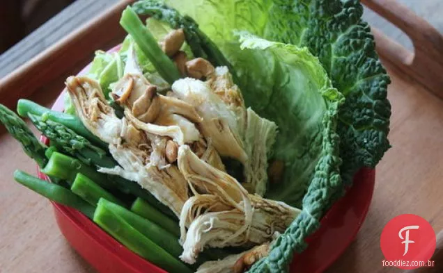 Frango escalfado com coco à frente com vegetais de primavera e castanha de caju