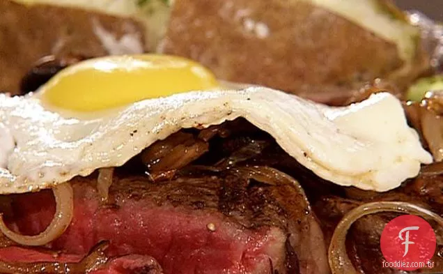 Bife T-Bone marinado com cerveja, cebola refogada e cogumelos, coberto com um ovo frito