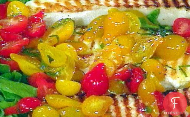 Bifes de alabote grelhados em uma cama de rúcula com salada de tomate e Gremolata