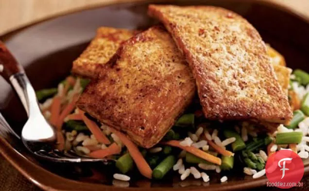 Tofu envidraçado com pimenta sobre aspargos e arroz