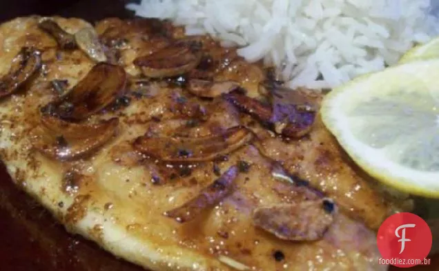 Filetes de peixe salteados com alho fatiado e molho de manteiga